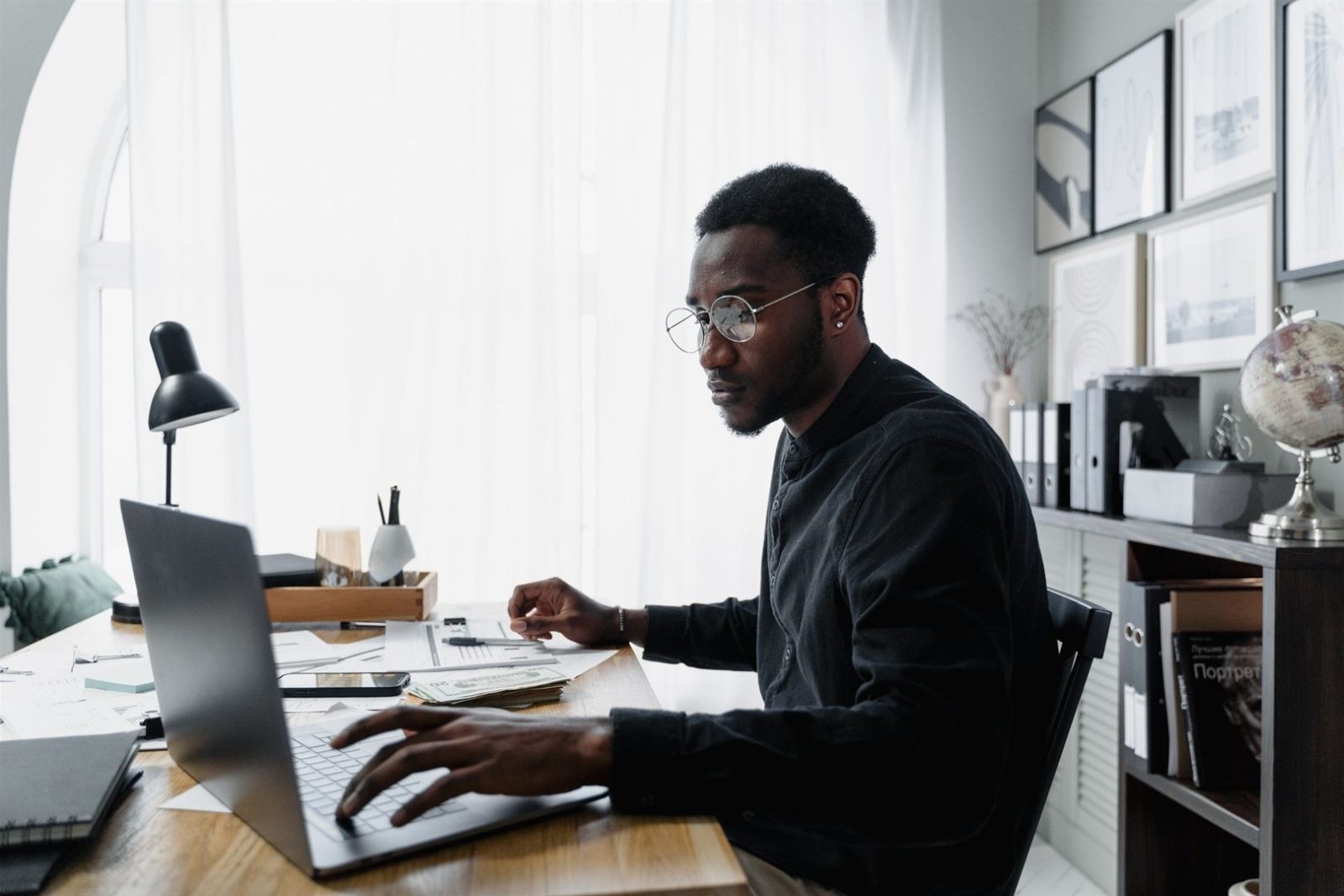 Entrepreneur noir concentré sur son ordinateur portable dans un bureau lumineux